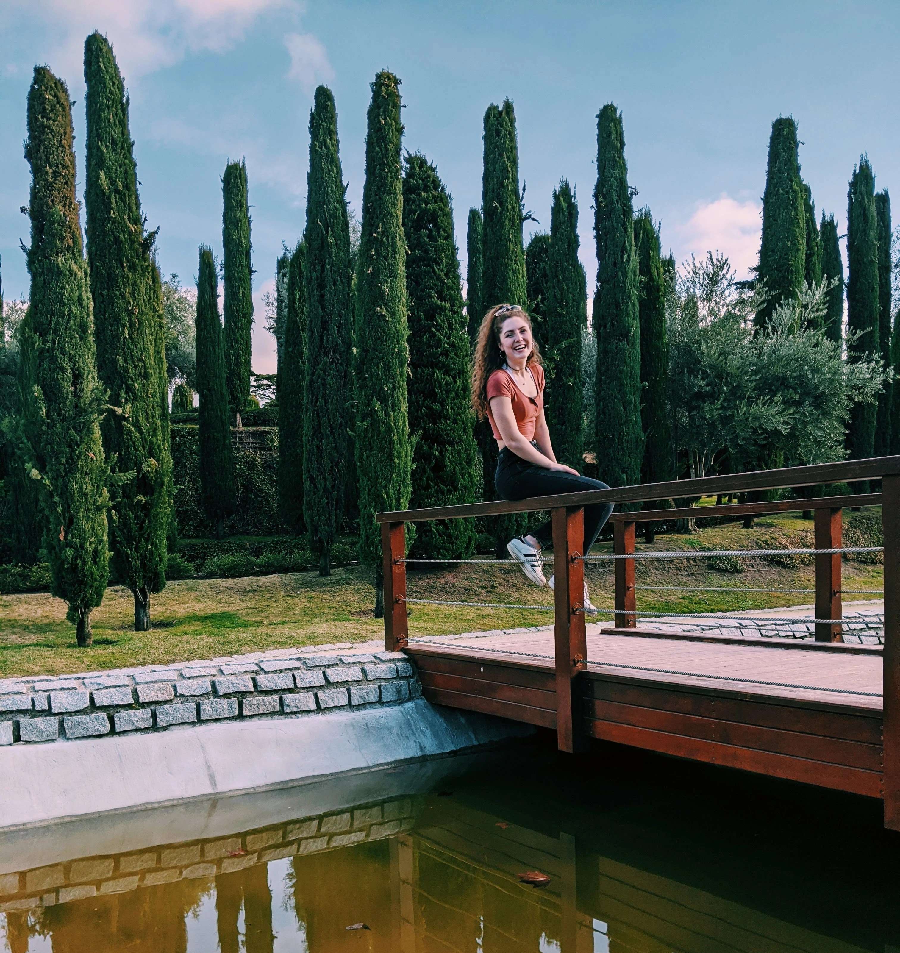 Liz sitting in Parque el Retiro on a bridge in Madrid