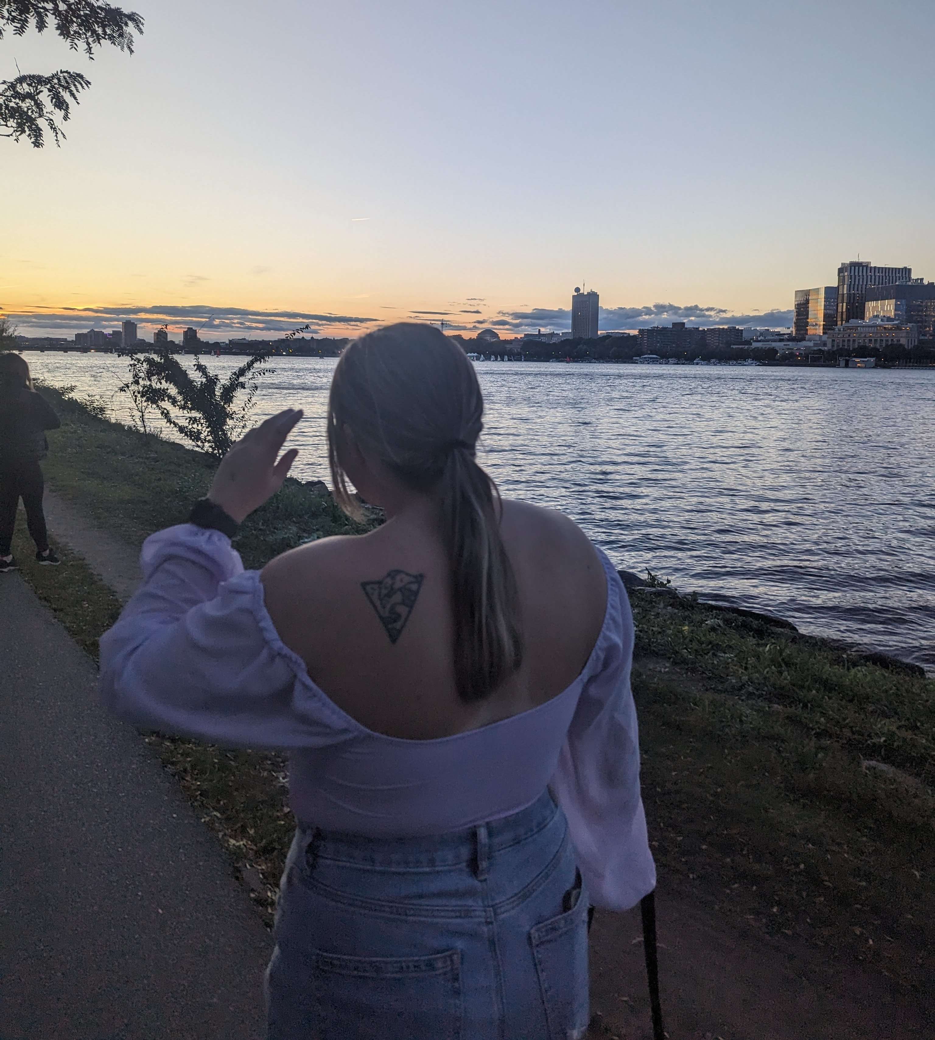 My friend walking along the esplanade along the path that runs along the Charles River with the buildings behind her.