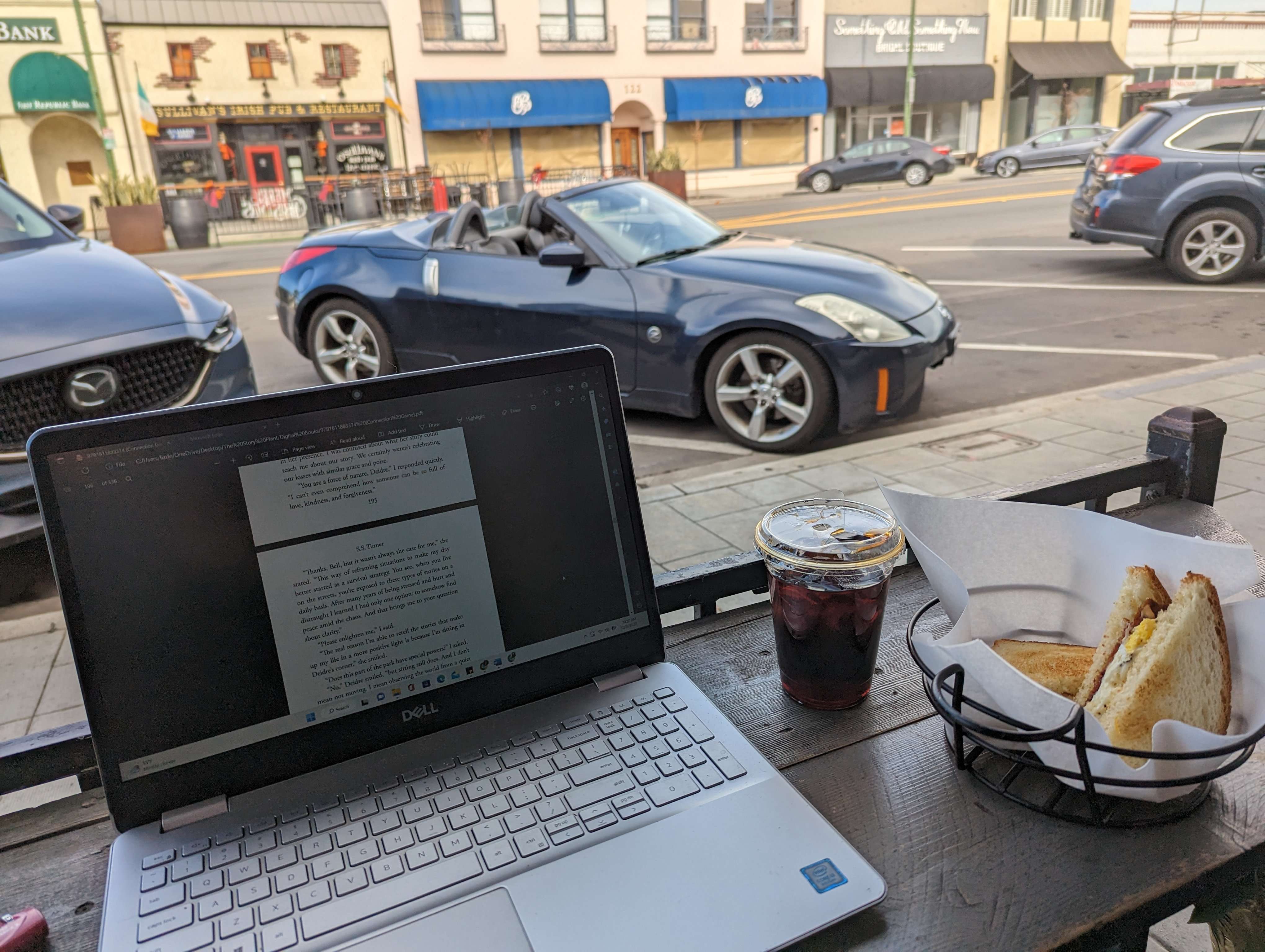 Computer Open for Work at a Cafe in California with a Coffee in front of me and some nice cars.