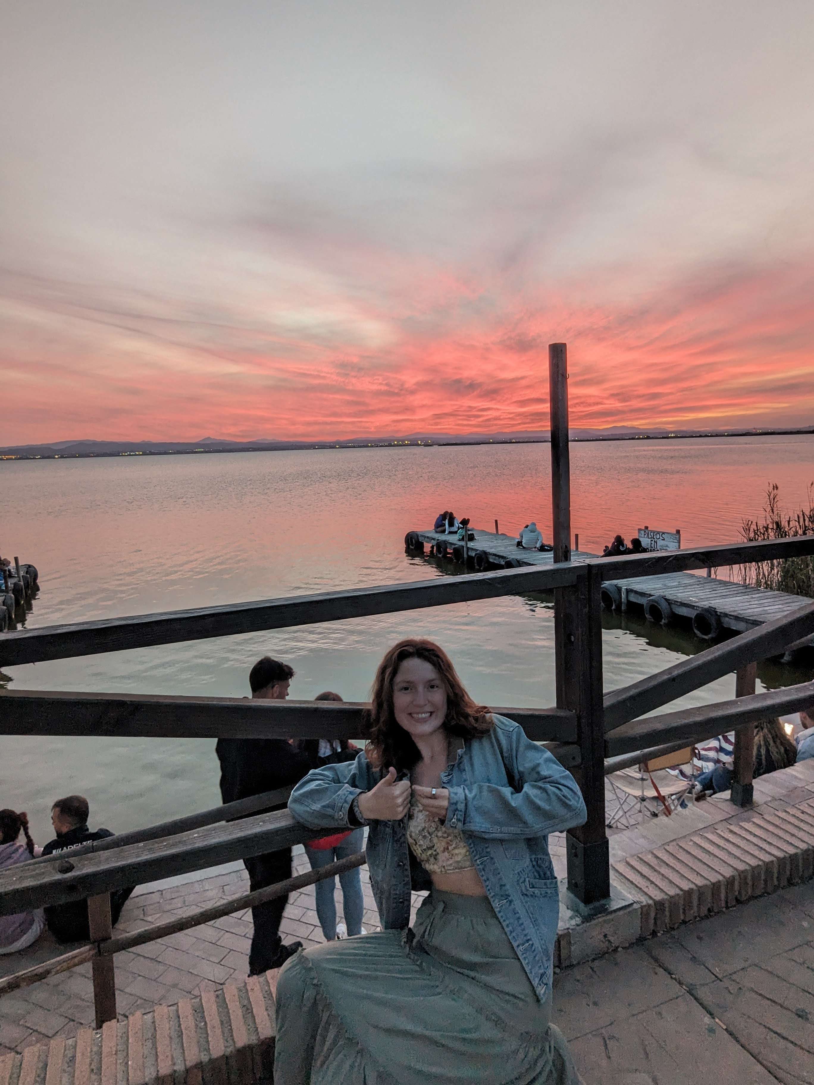 Me (Traveler Liz) with my thumbs up in front of a gorgeous pink sunset view at Albufera National Park.