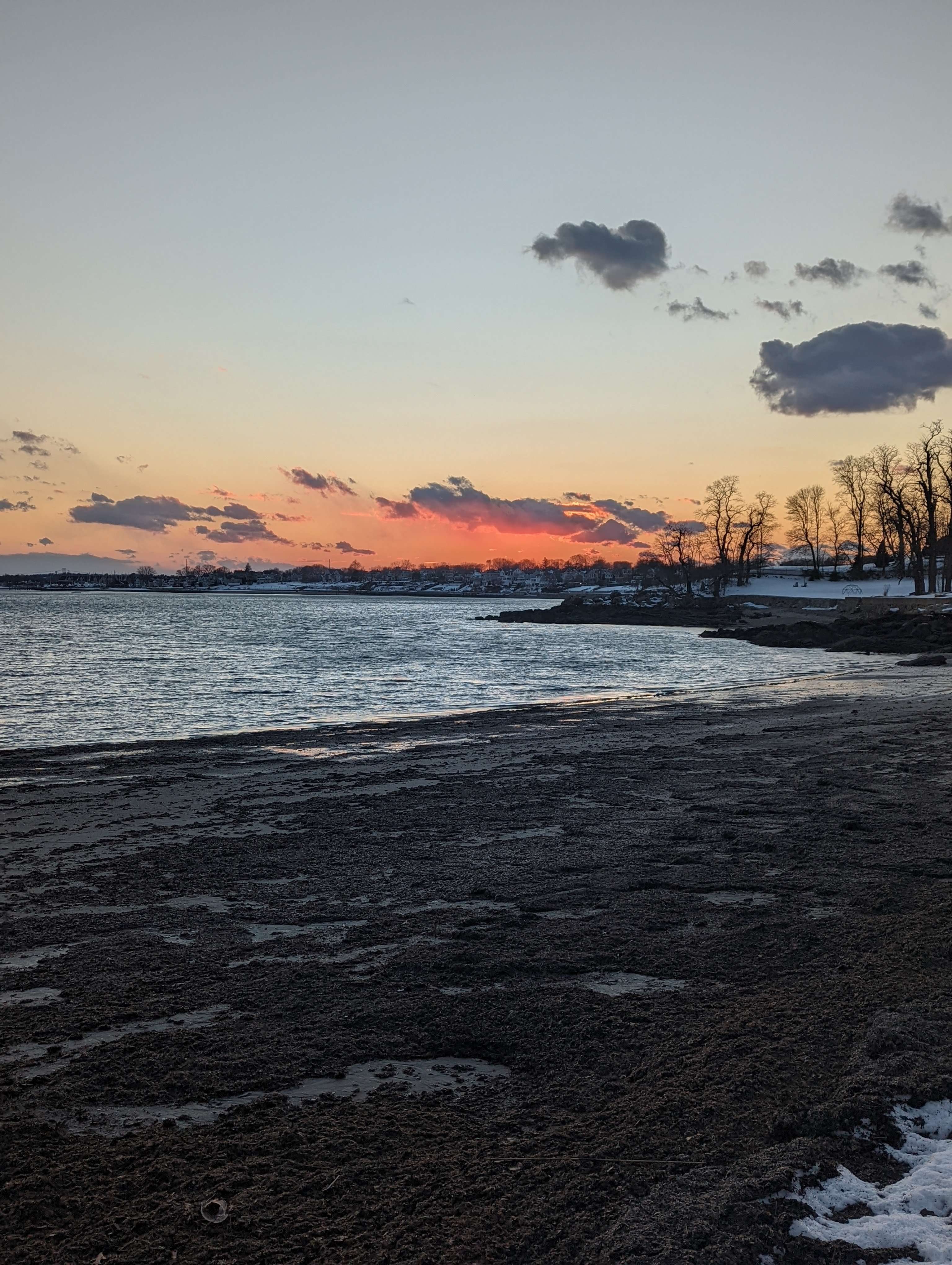 A beach front sunset with snow-covered sand.