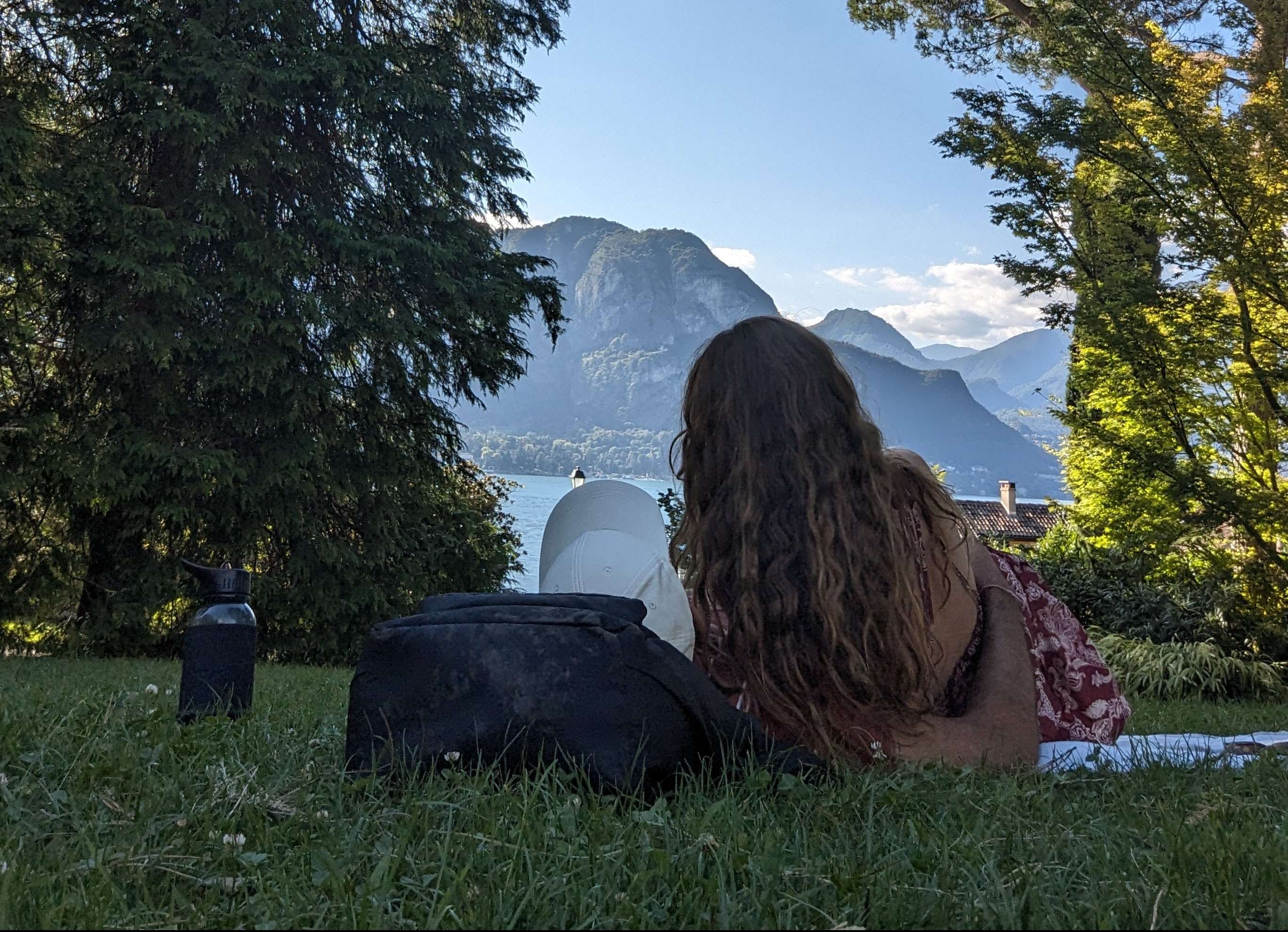 A couple laying in a park staring out at Lake Como.