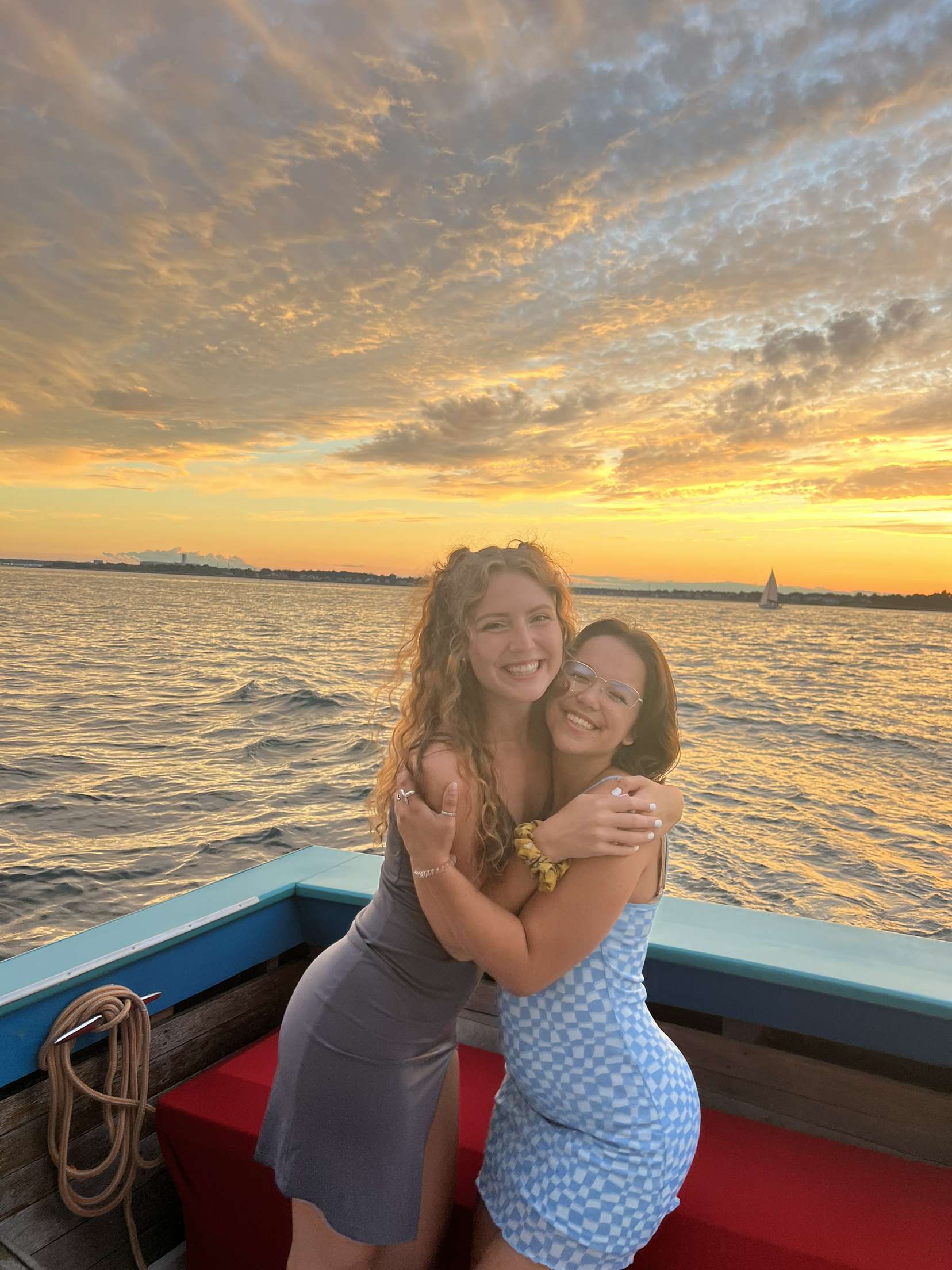 My friend and I (Traveler Liz) on a boat in front of a gorgeous orange- hued sunset.