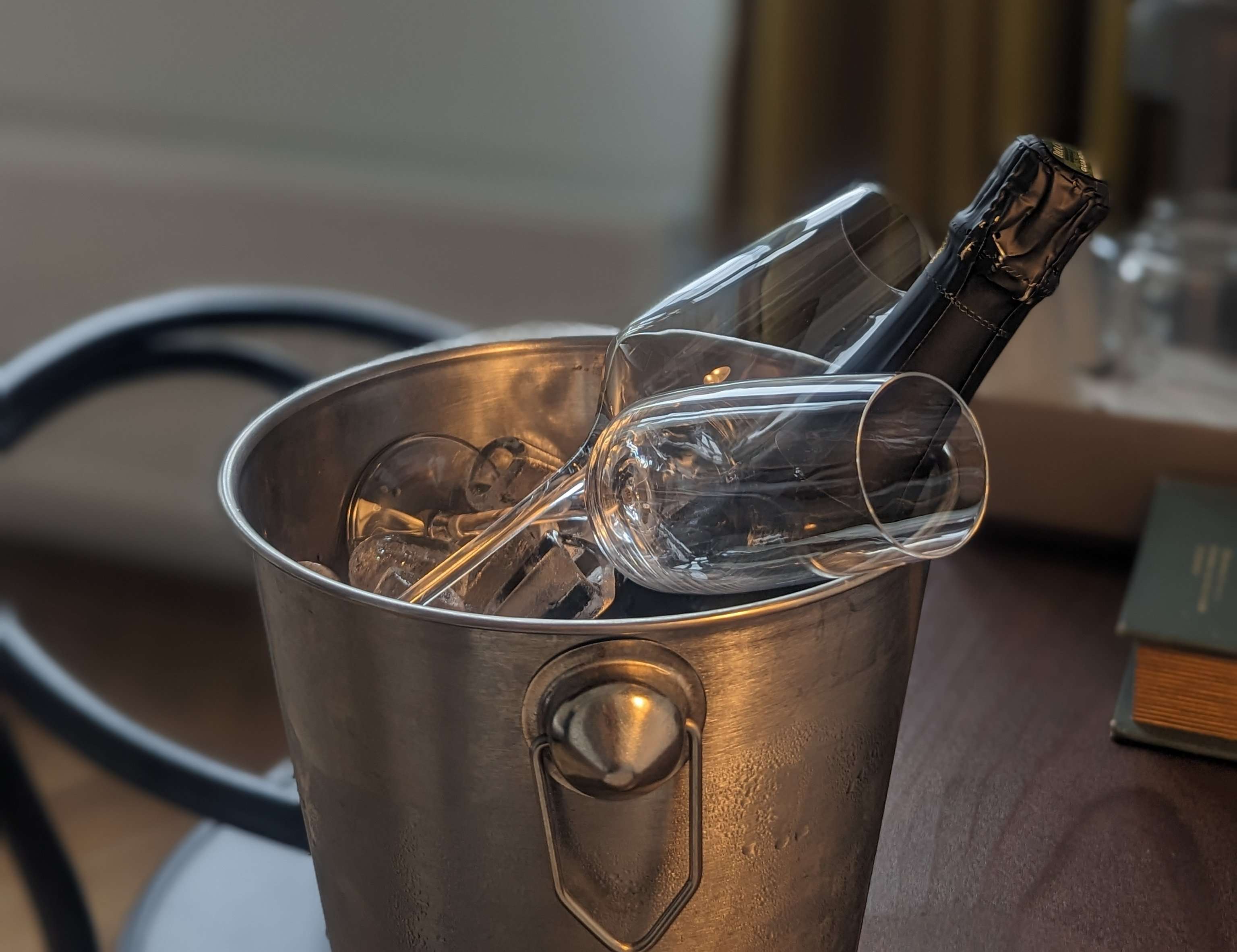 A bucket of Champagne with two glasses placed inside sitting on a table in my hotel room.