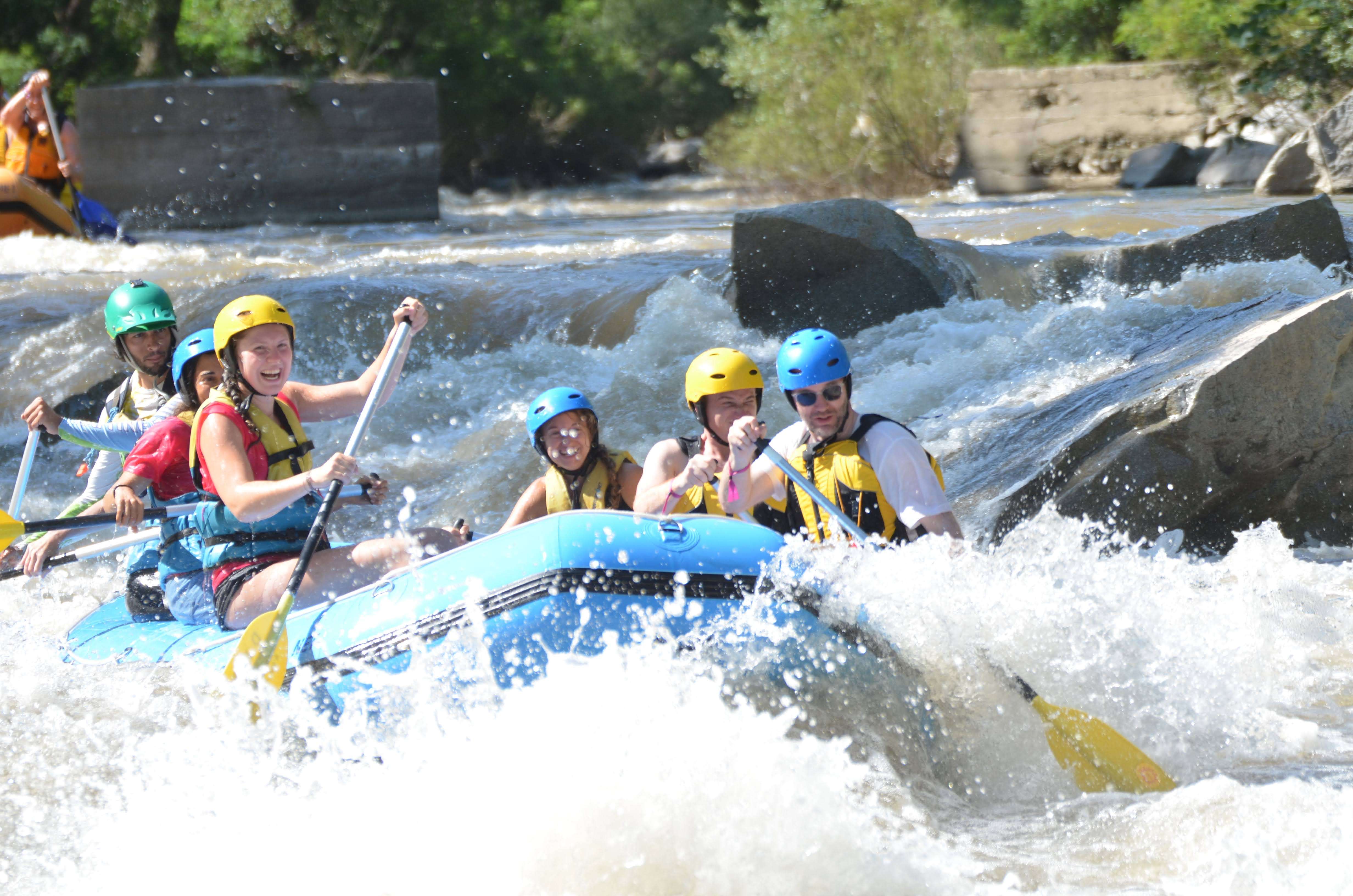 A group of friends hitting a jump while whitewater rafting.