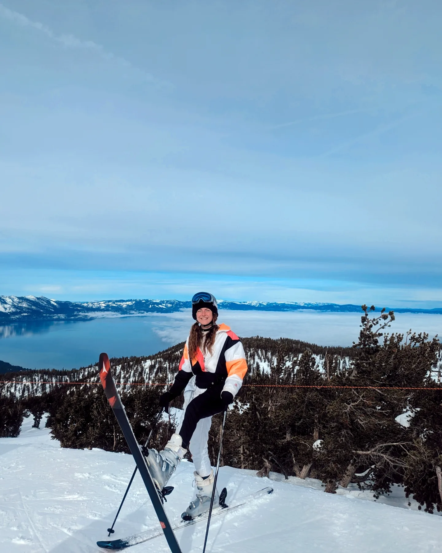 Me (Traveler Liz) with skis on in front of Lake Tahoe in California.