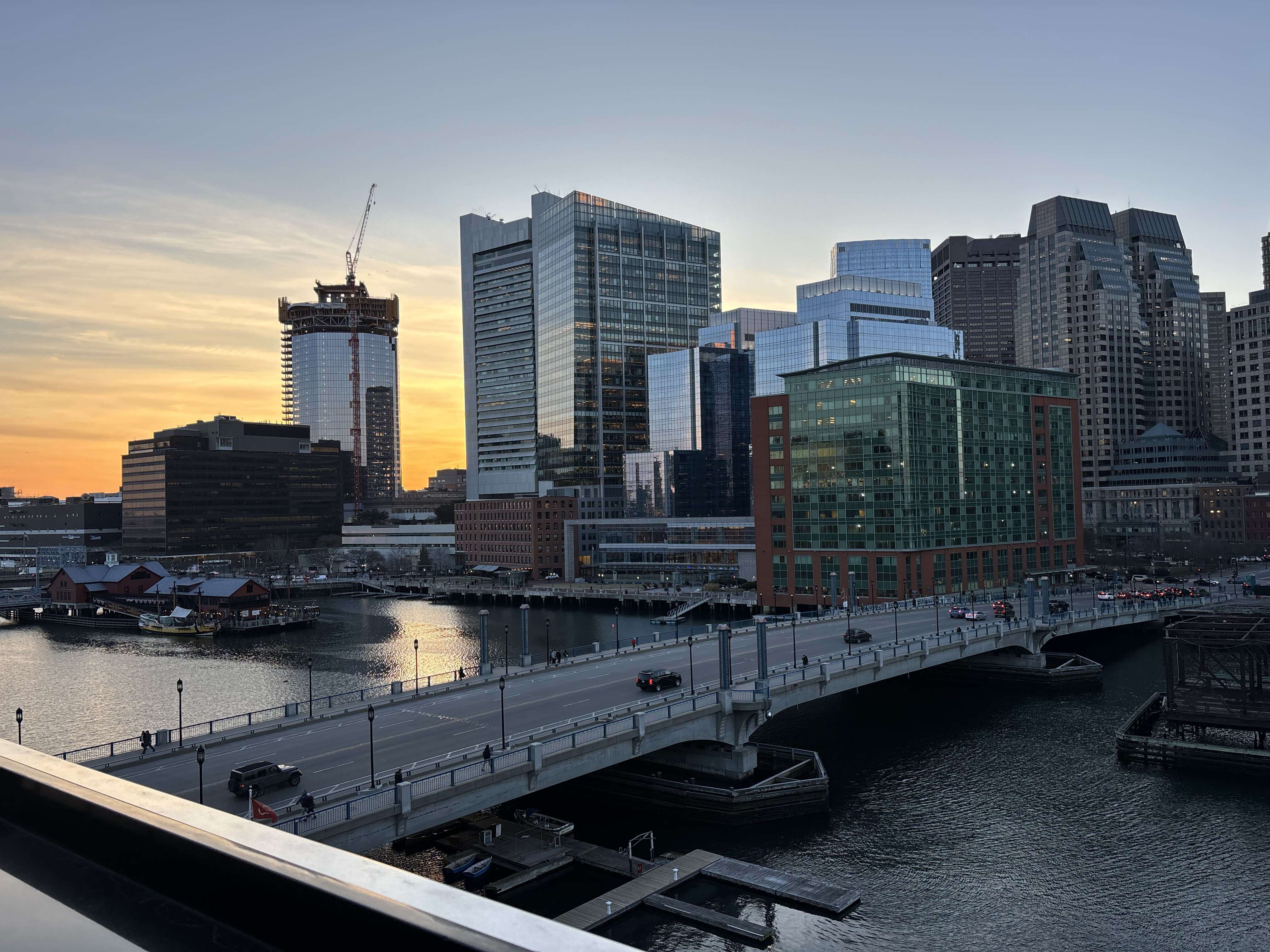 The same Boston skyline visual from the first picture at sunset, so the only light is orange and behind the buildings.
