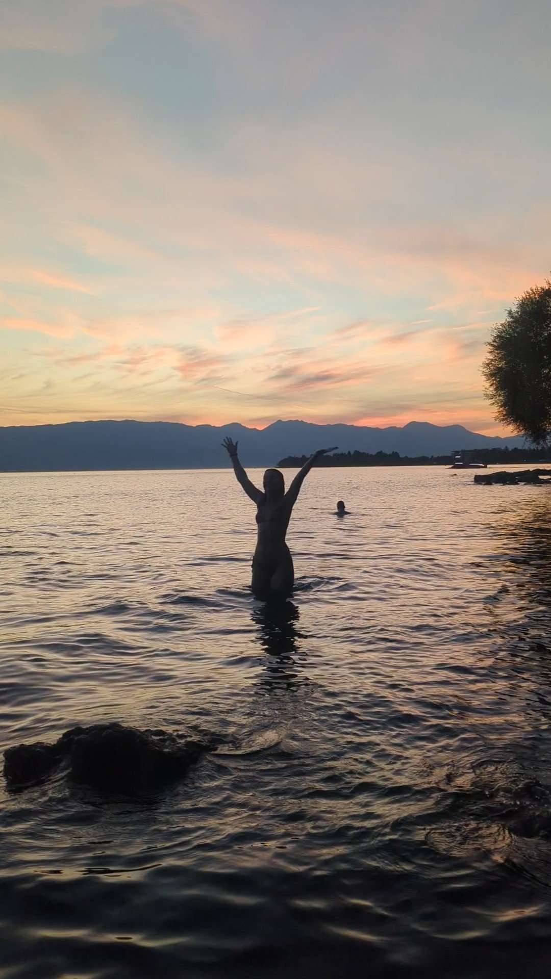 My silhouette in Lake Ohrid with hands up in front of the mountains. 