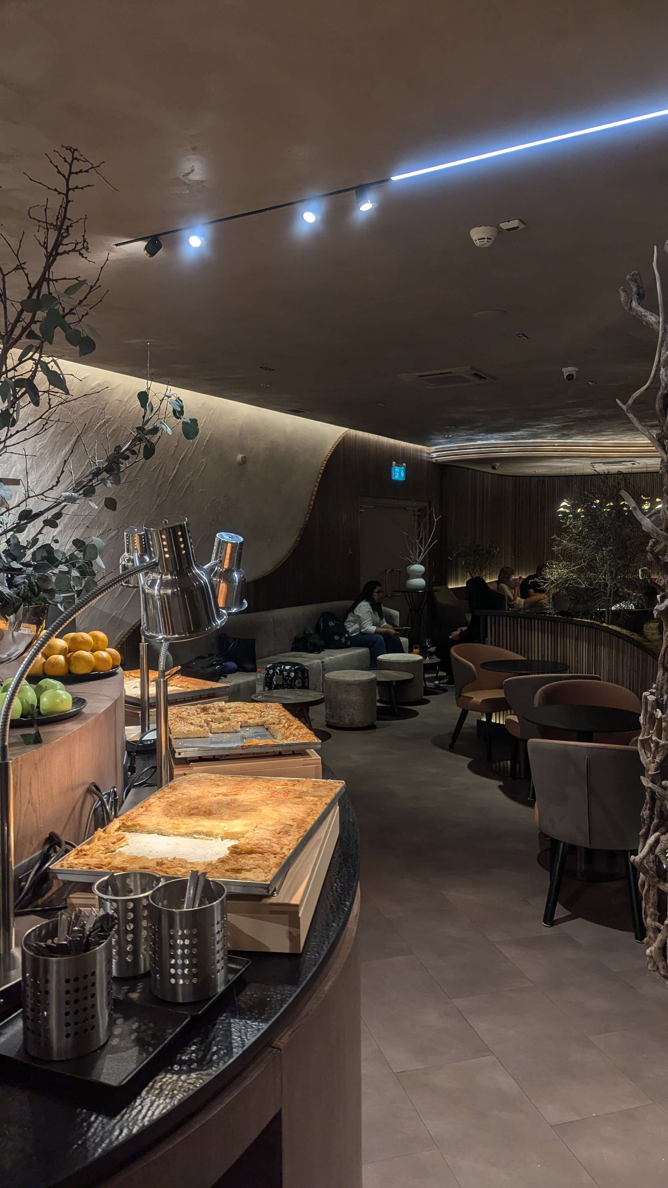 An airport lounge with Albanian food out and comfortable charis.