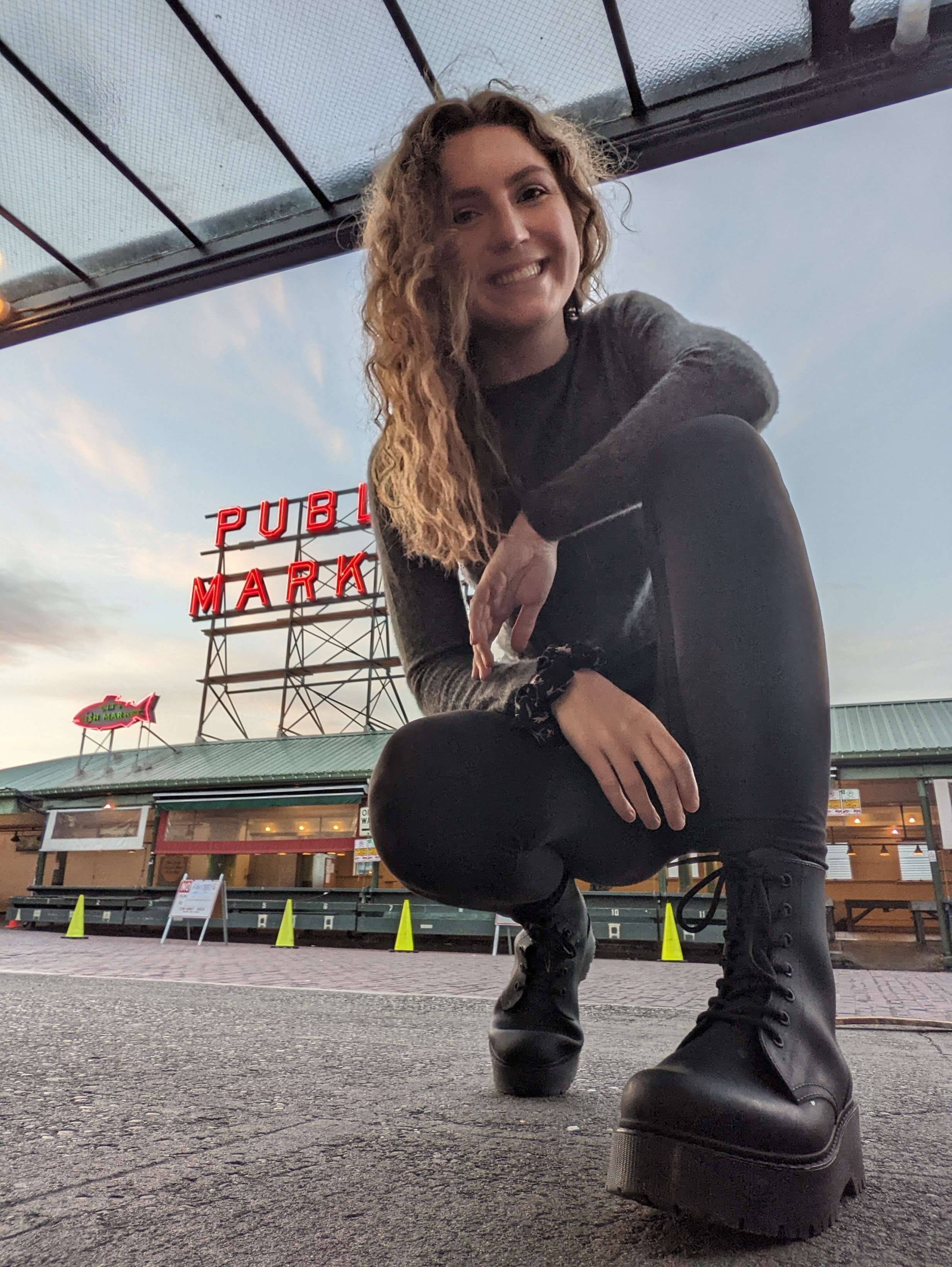 Me (Traveler Liz) crouched down in front of the Public Market sign in Seattle.