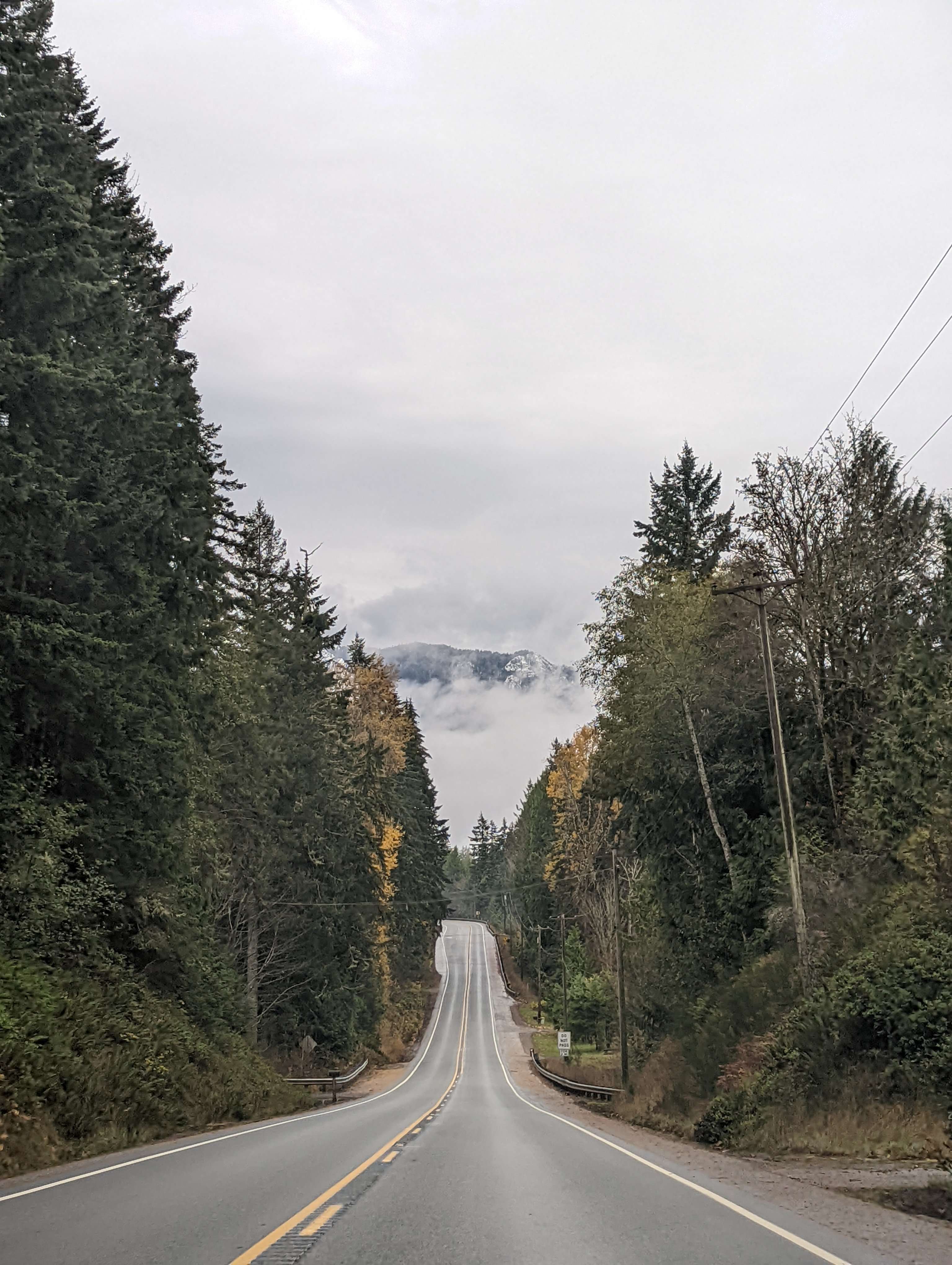 The road towards Olympic National Park with fog and a mountain in the background.