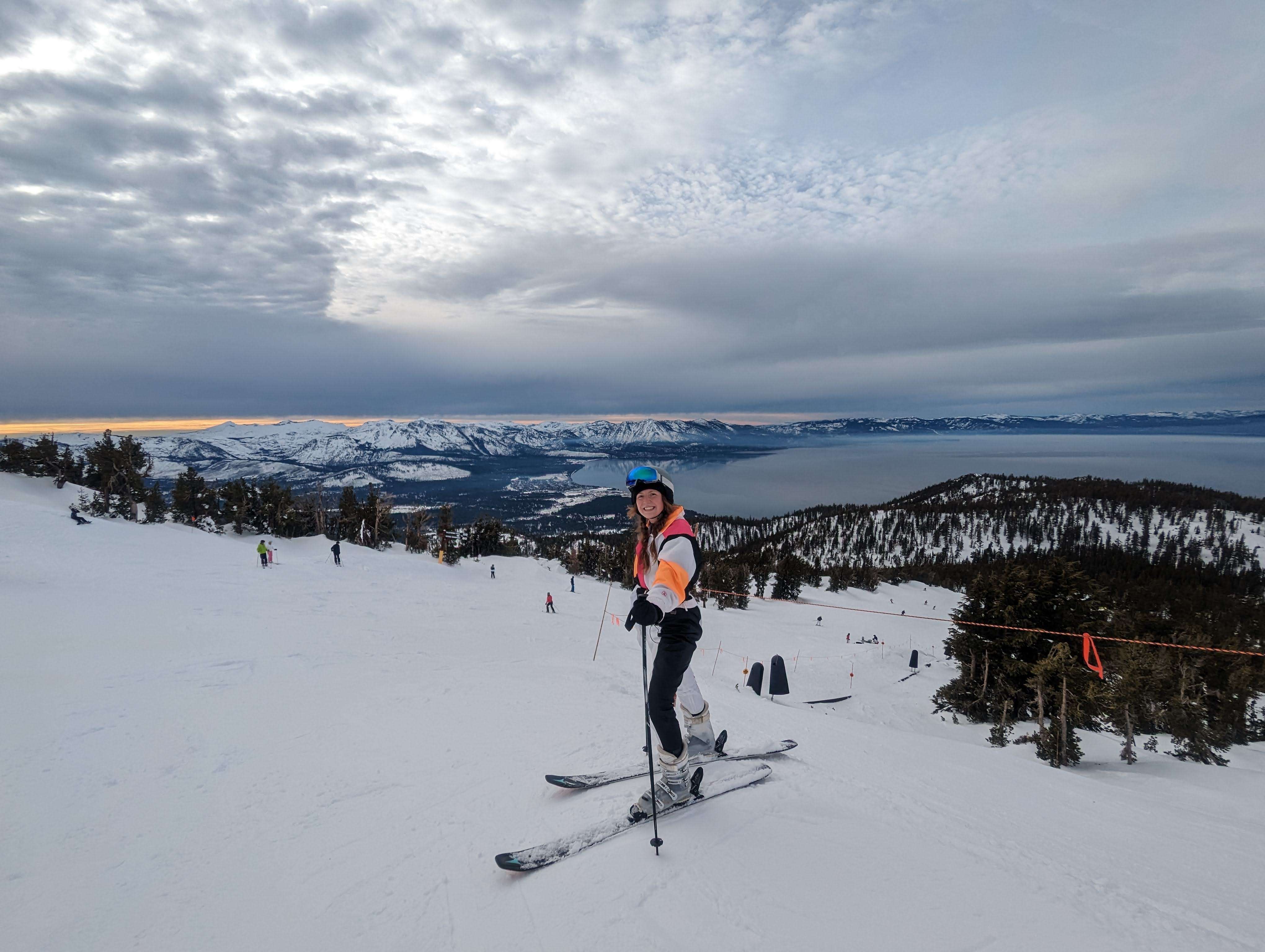 Traveler Liz on top of Heavenly Mountain with skis and the lake behind her
