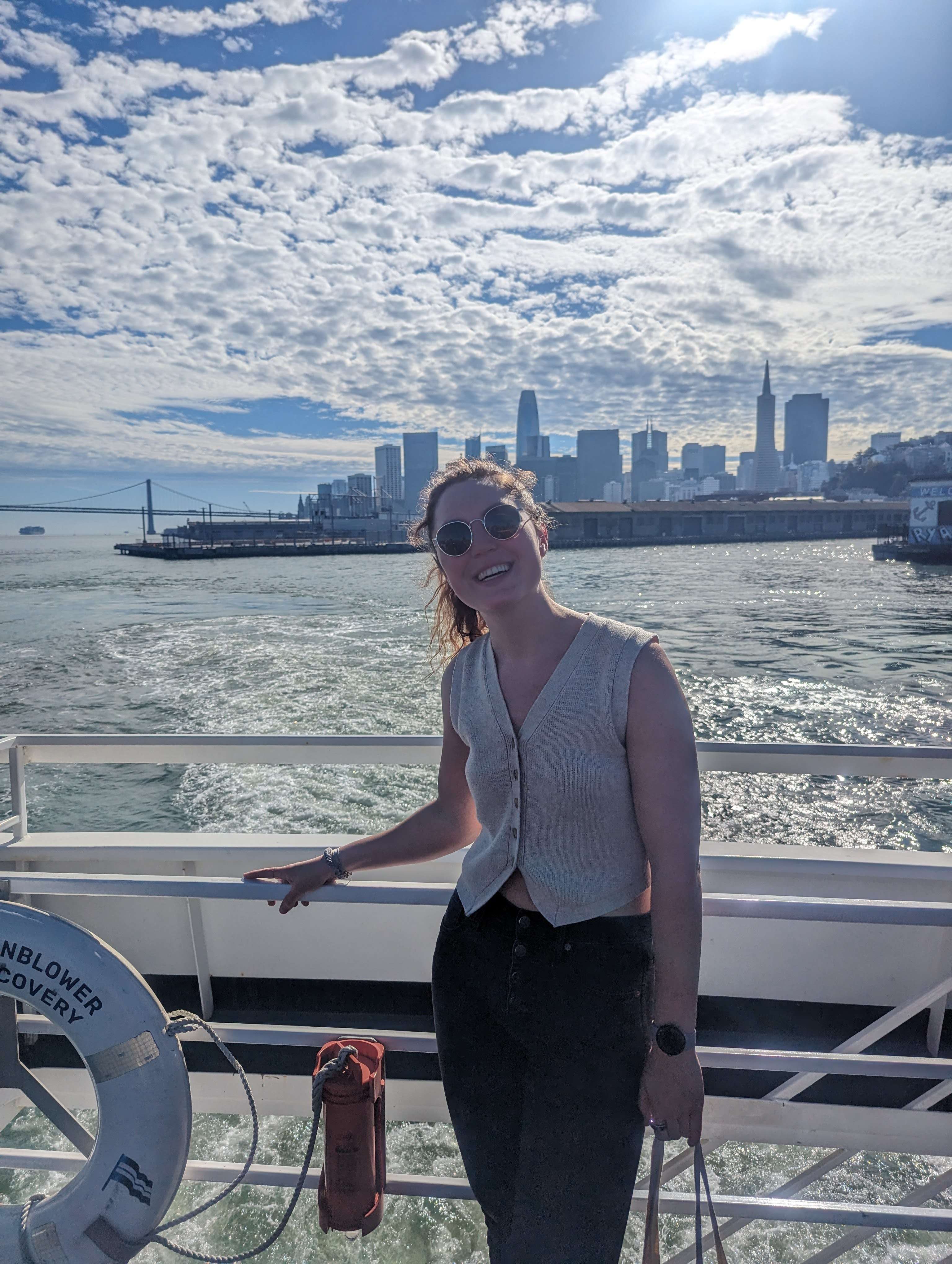Traveler Liz on a boat headed to Alcatraz with San Francisco skyline behind her.