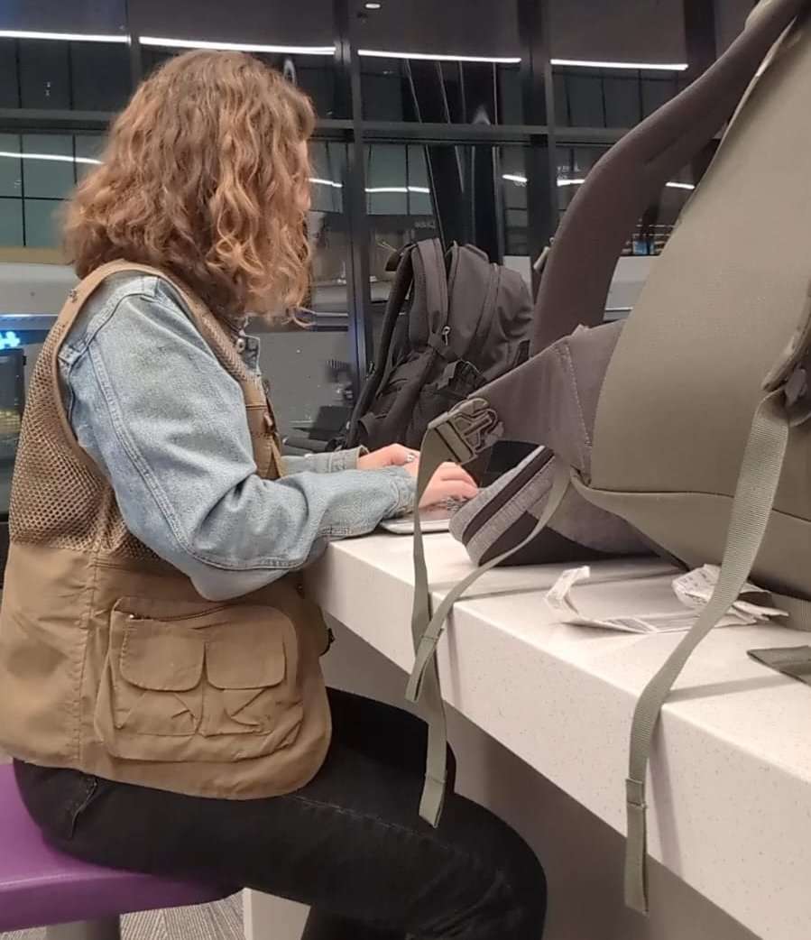 Traveler Liz sitting with her bags wearing her fishing vest.