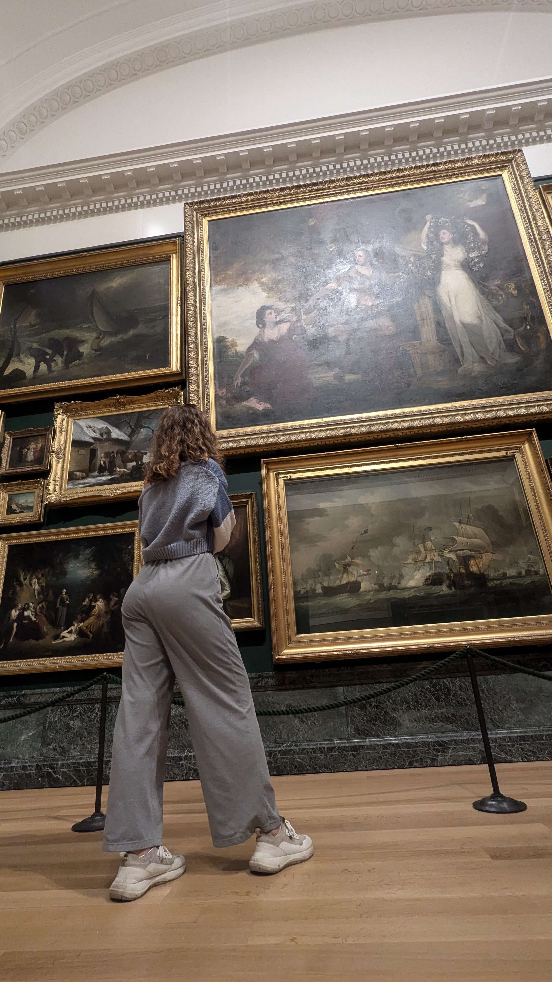 Traveler Liz standing in front of paintings at a museum in London.