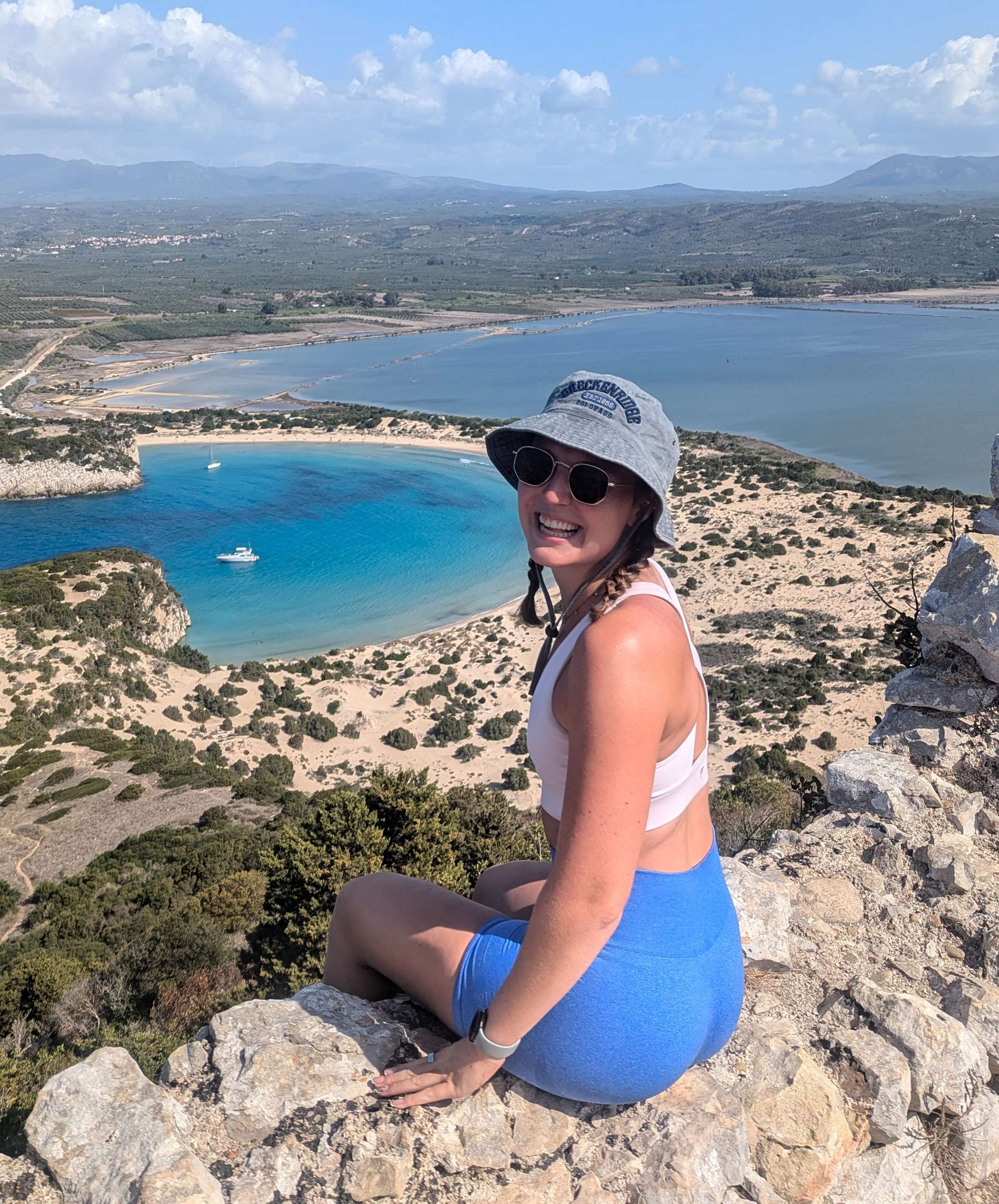 Traveler Liz sitting on a cliff overlooking Navarino Bay in Greece