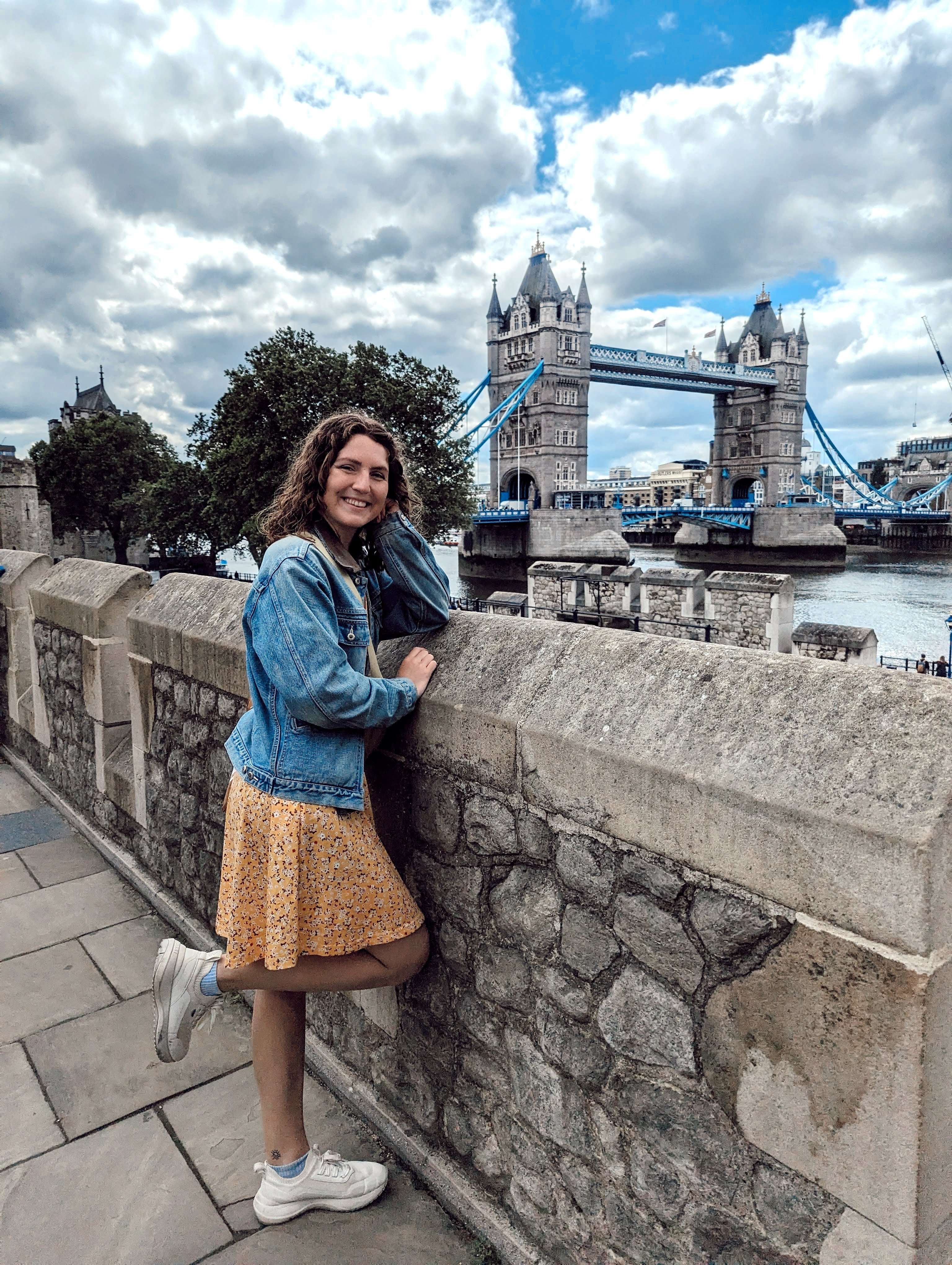 Traveler Liz at the Tower of London with the Tower Bridge in the background.