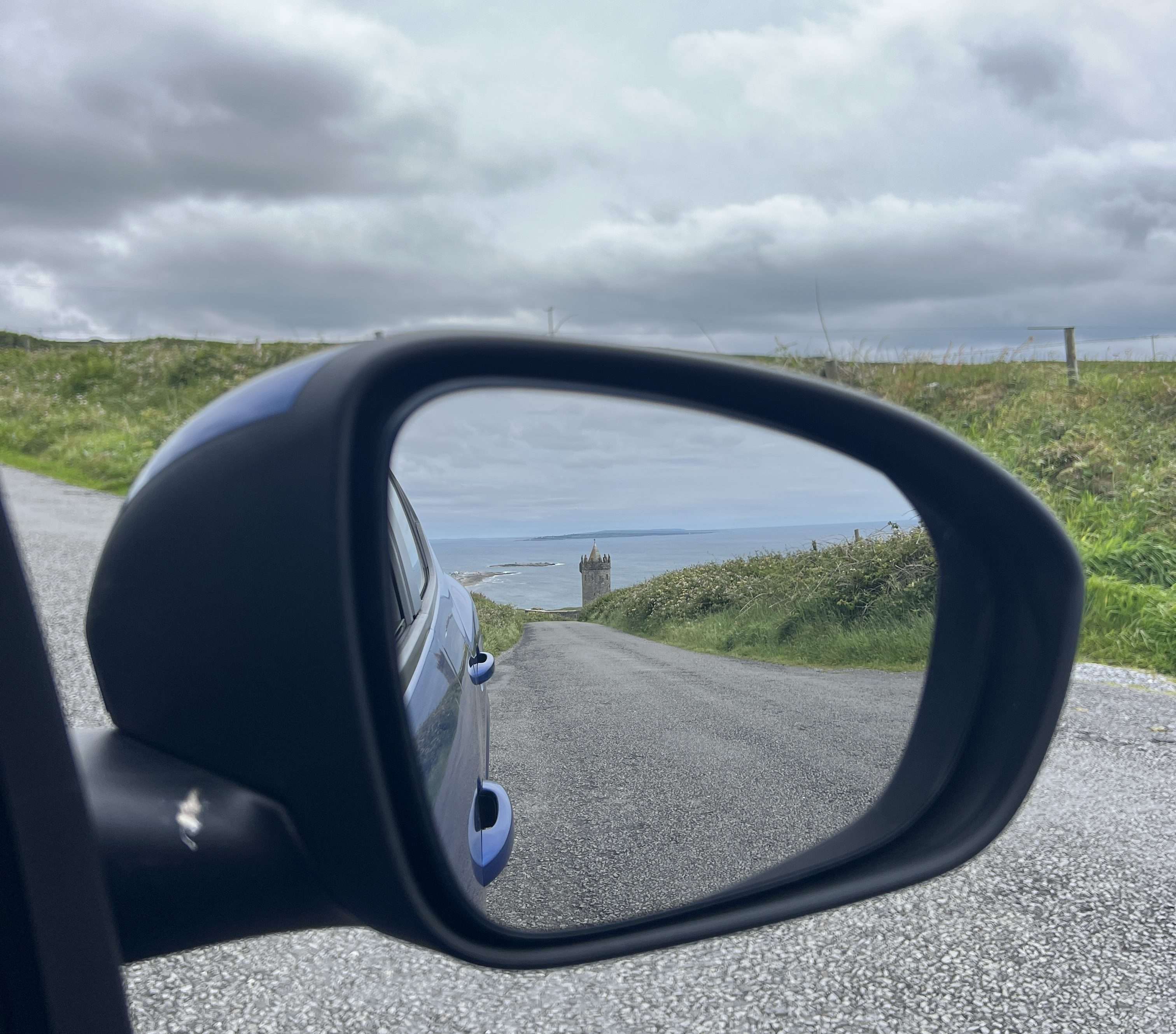 Car side mirror in Ireland looking back at Doolin and the roads in Ireland