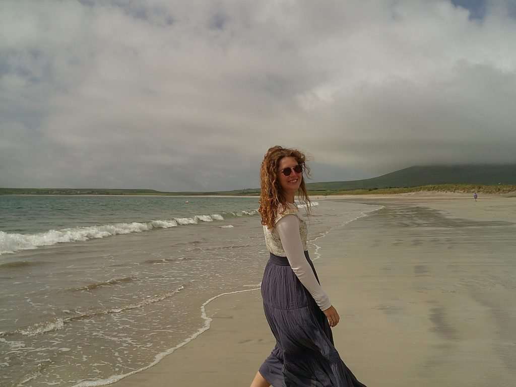 Liz standing on a beach in Ireland on a typical moody day.