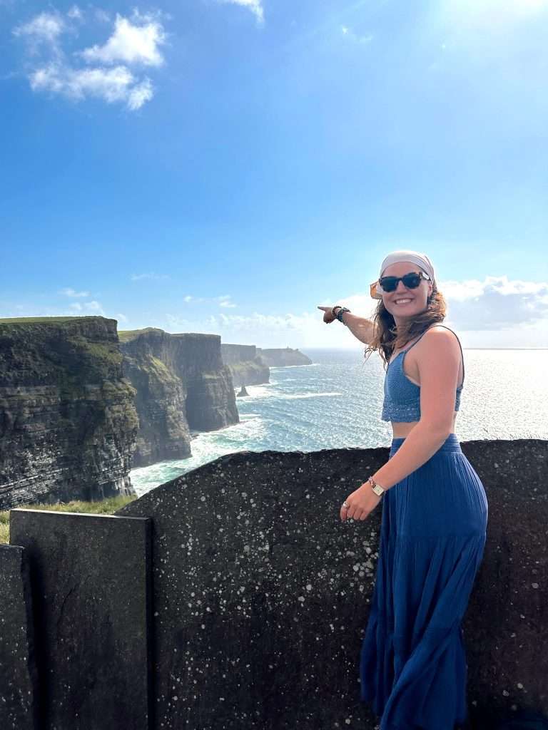 Liz pointing at the Cliffs of Moher in Ireland.