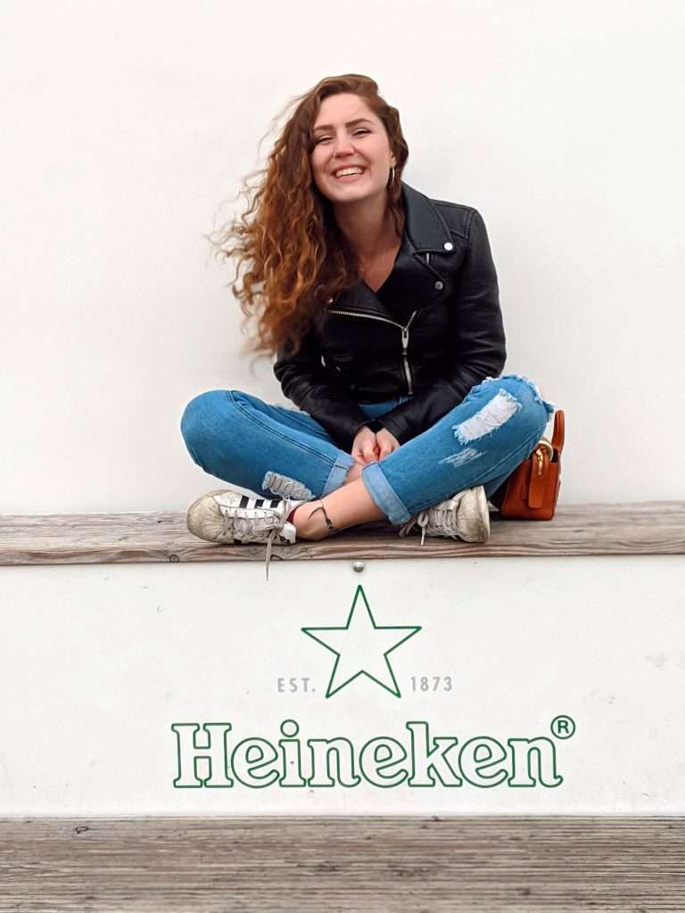 Traveler Liz sitting and smiling on the roof at the Heineken Experience