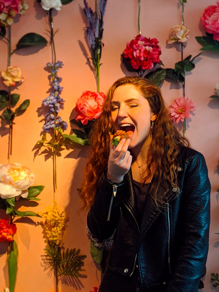 Traveler Liz about to bite into a chocolate covered strawberry near nine streets in Amsterdam