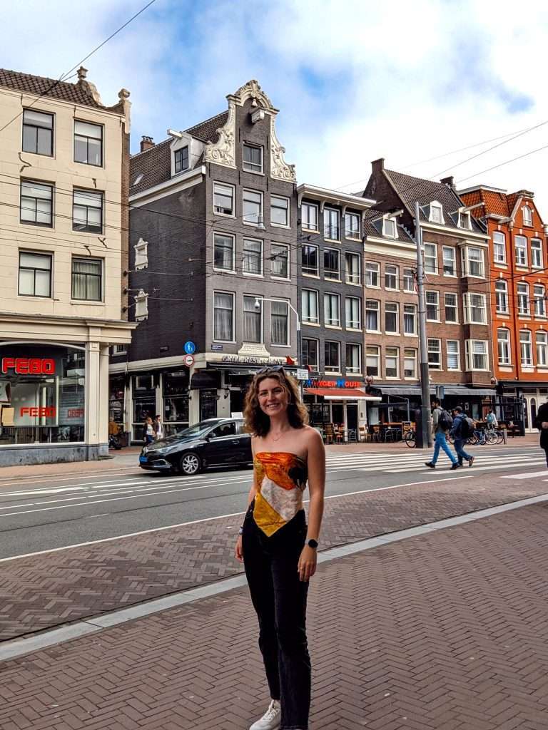 Traveler Liz posing in front of some buildings in Amsterdam