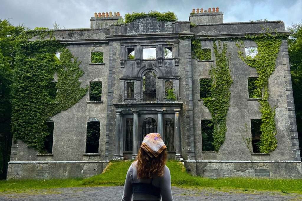 Moore Hall ruins covered in ivy in Ireland with Liz staring at it.