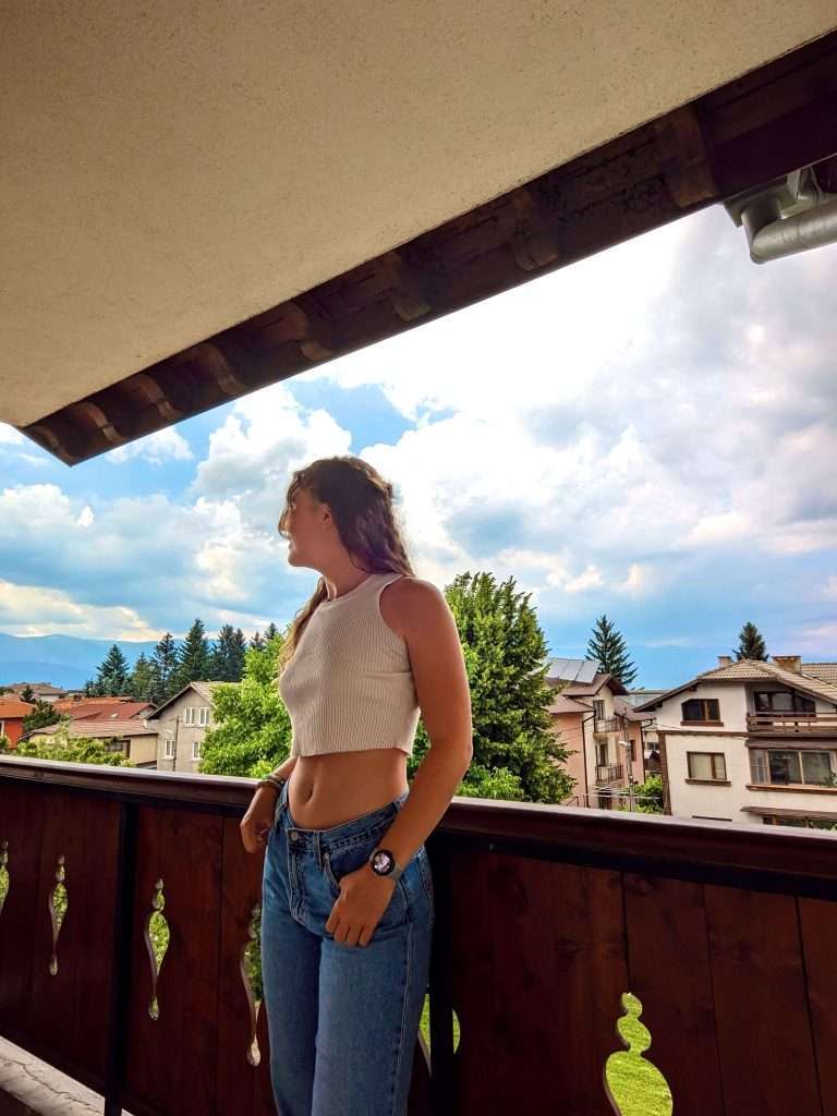 Liz and the balcony view of Guest House Ilinden where you can stay in Bansko.