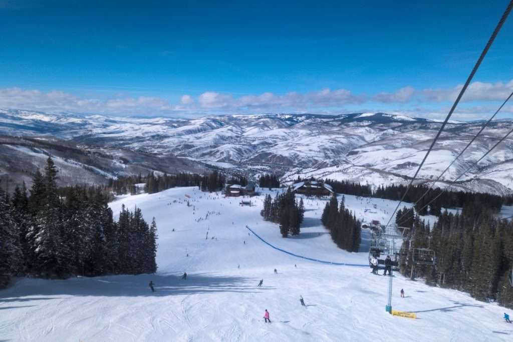 Bluebird ski day at Beaver Creek Resort, Colorado, with skiers on wide open runs, pine trees, and snow-covered mountains in the distance — one of the top Epic Pass resorts in Colorado.