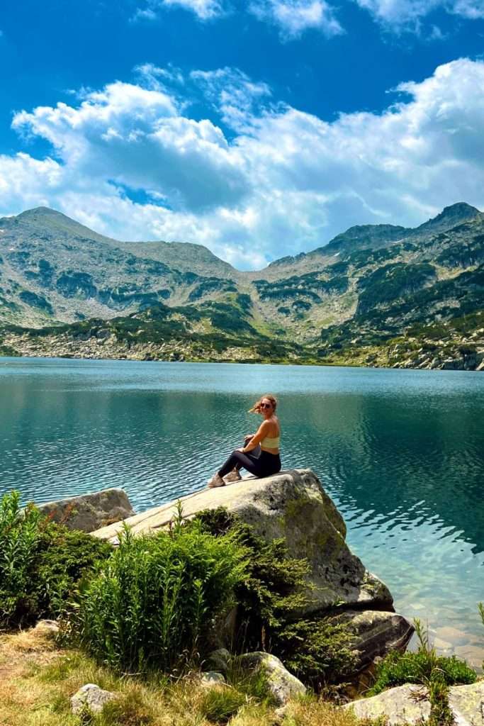 Traveler Liz sitting in front of a lake in Bulgaria during a hike.