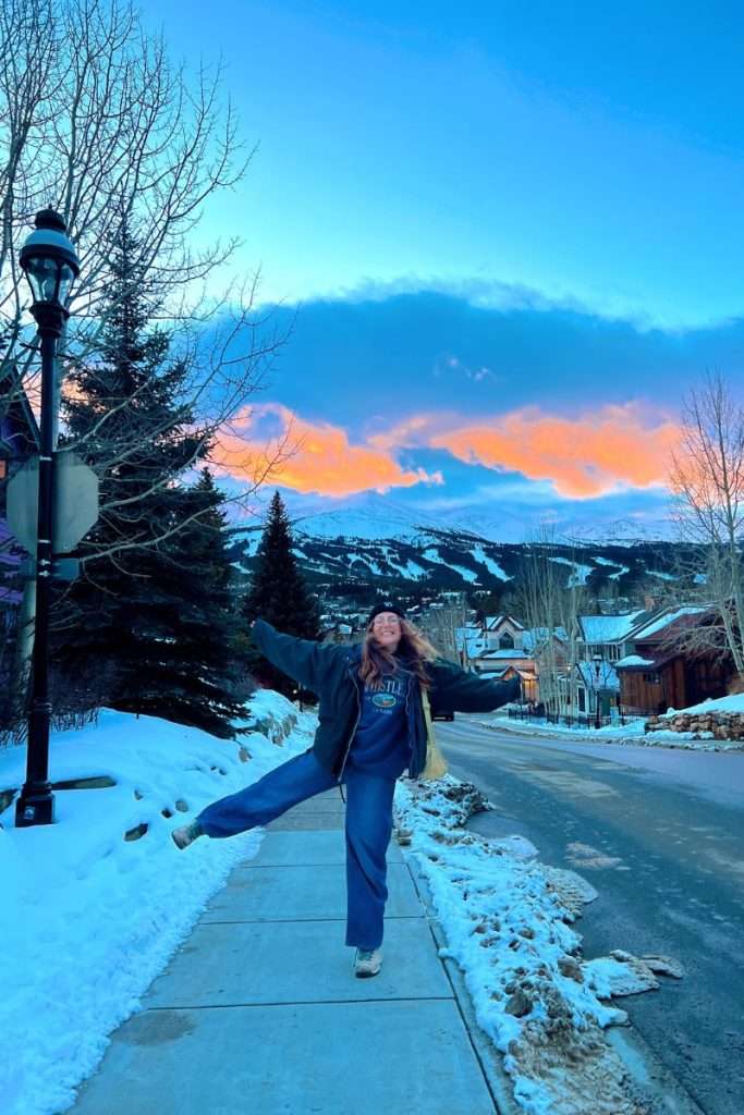 Traveler Liz with the mountains and the sunset behind her in Breckenridge