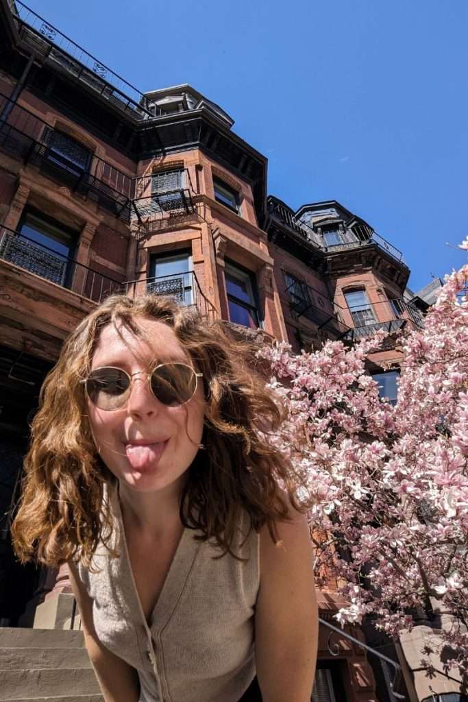 Traveler Liz in Back Bay in front of the cherry blossoms and the iconic brownstones