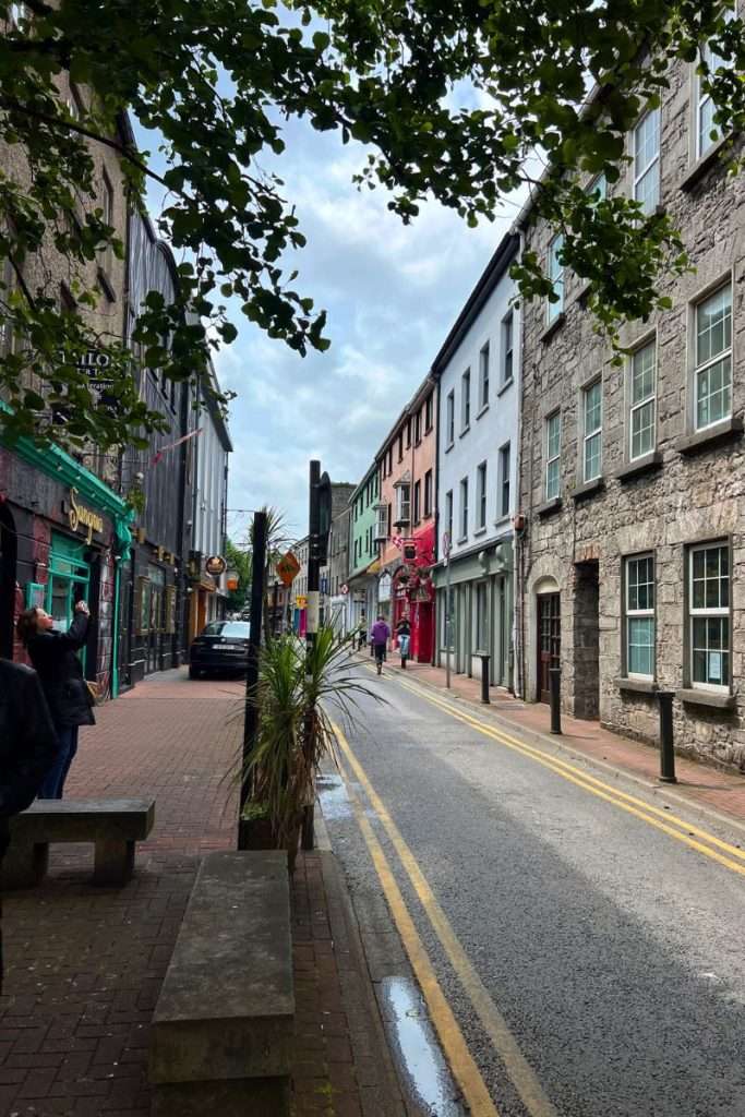 A city center in Ireland that is a very narrow road to drive through with colorful buildings.