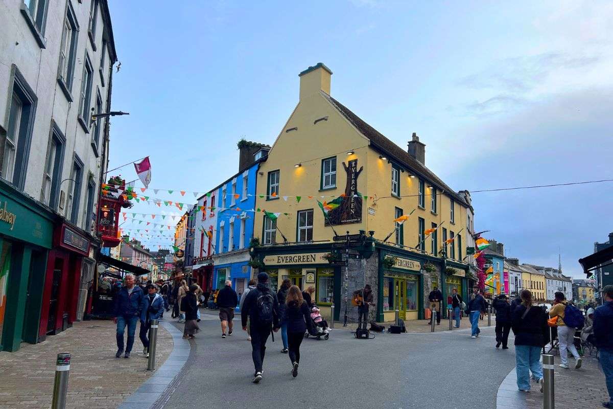 Colorful streets of Galway city with shops, flags, and people walking through the lively town center in Ireland