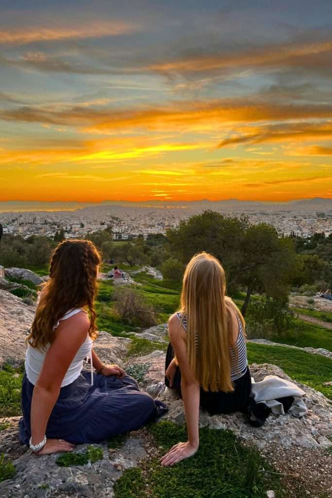 Traveler Liz and her friend having a picnic watching the sun set in Athens