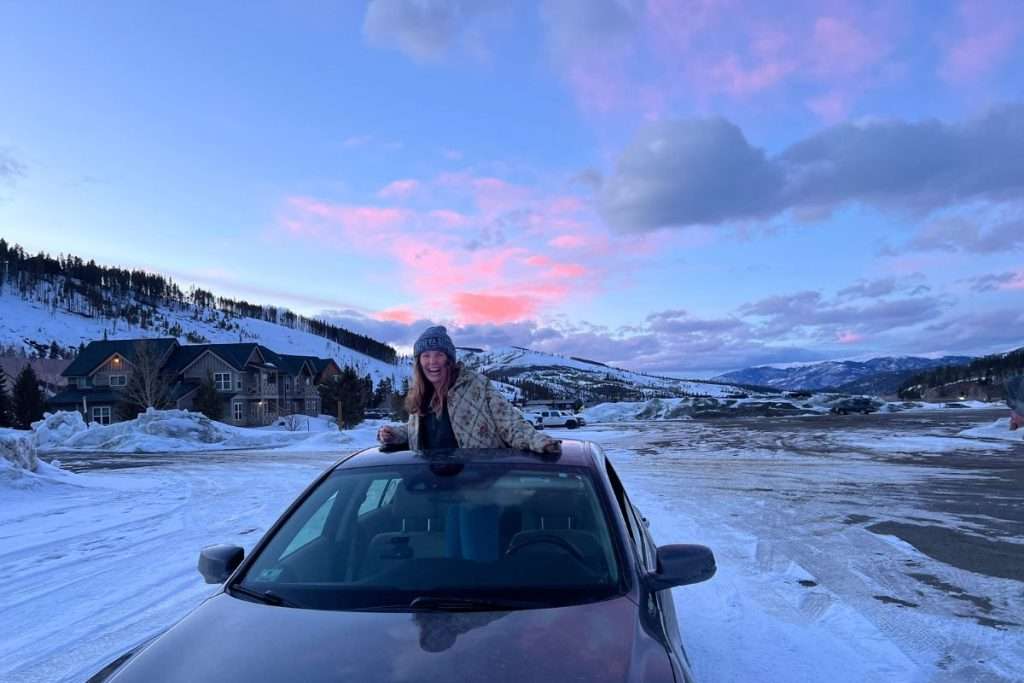Liz outside the sunroof of her car in the Colorado winter in Brekencirdge